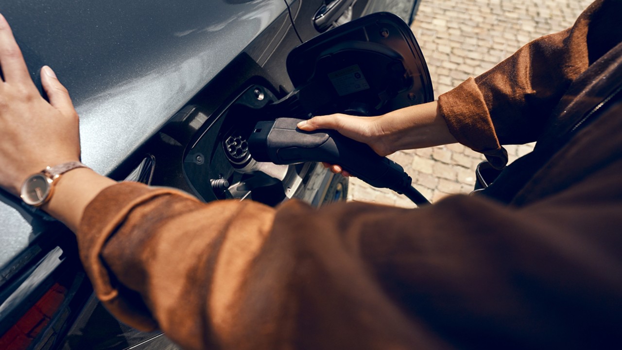 A person plugging in a charging socket into a Lexus NX 