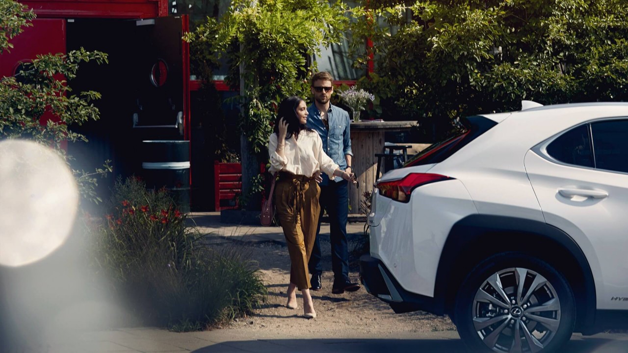 A man and a woman standing by a Lexus 