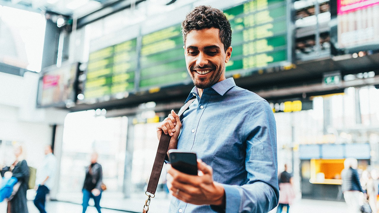 businessman standing at the railway station, checking his phone